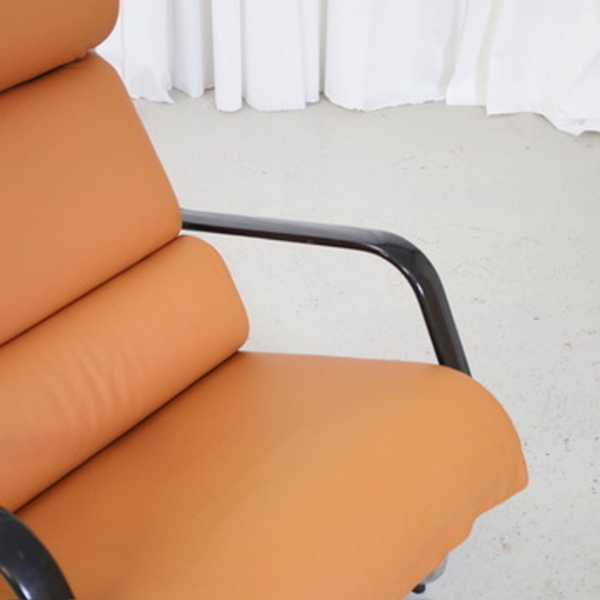 Detail of the cognac leather seat and black armrest on a Yrjö Kukkapuro Remmi chair