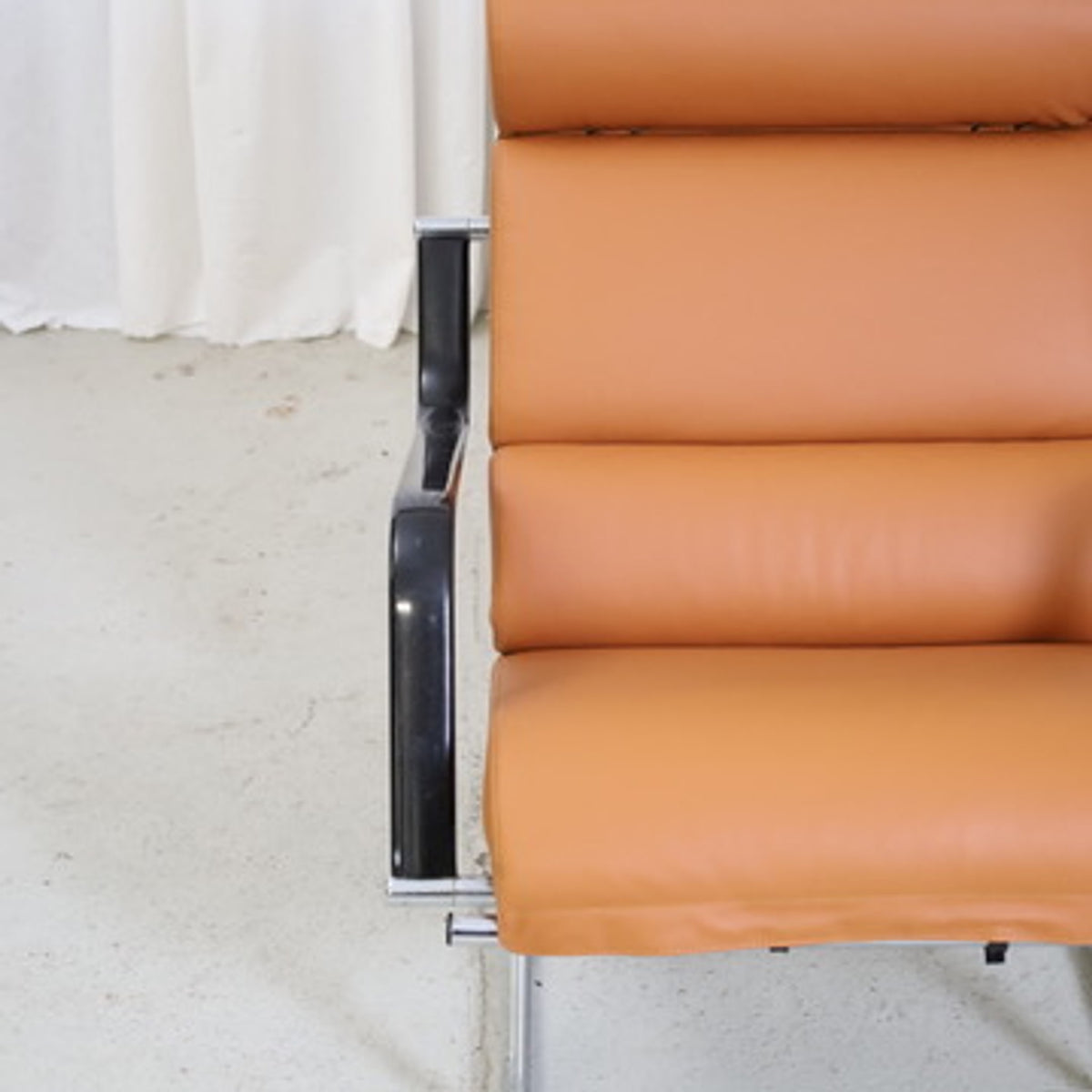 Front detail of the cognac leather upholstery and black armrest on a Yrjö Kukkapuro Remmi chair